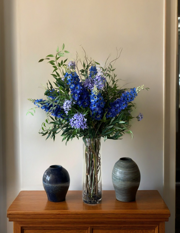 Arreglo Floral de Delphiniums y Agapanthus con Follajes Artificiales en Florero de Vidrio