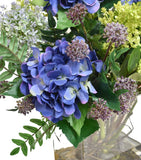 Arreglo Floral de Hydrangeas en Tonos Lila y Follajes Artificiales en Base de Vidrio con Agua Acrílica