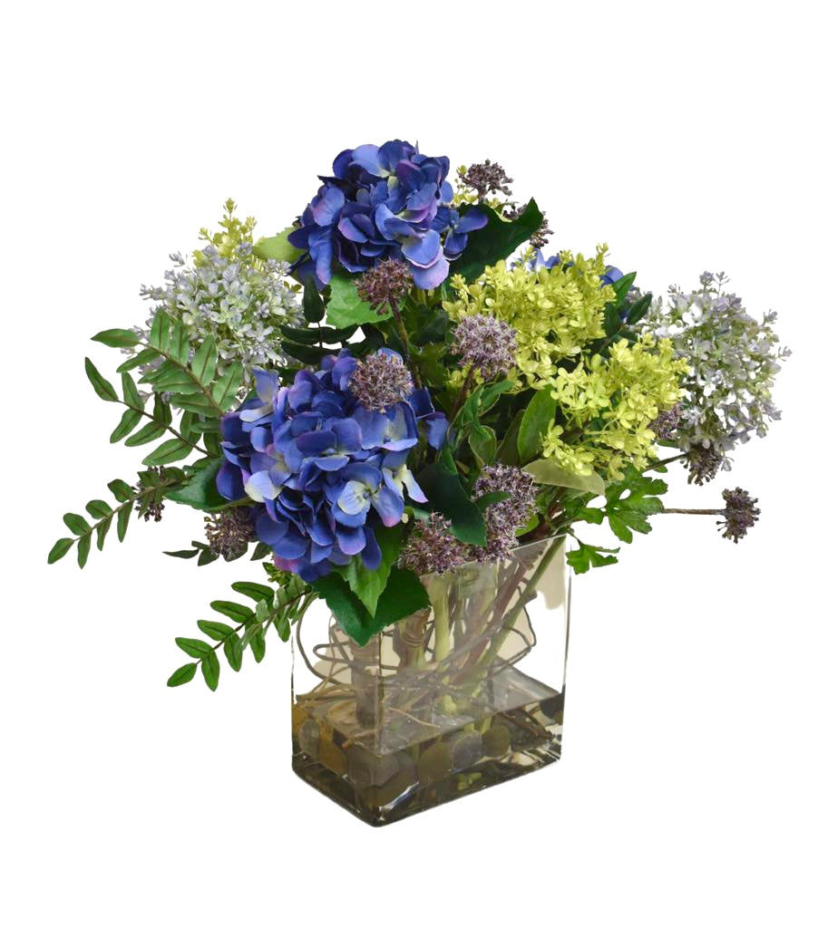 Arreglo Floral de Hydrangeas en Tonos Lila y Follajes Artificiales en Base de Vidrio con Agua Acrílica