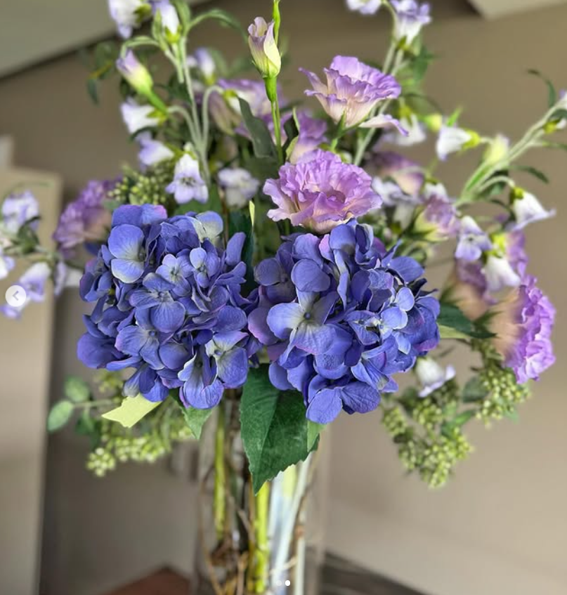 Arreglo Floral con Lisianthus e Hidrangeas y Follajes Artificiales en Florero de Vidrio