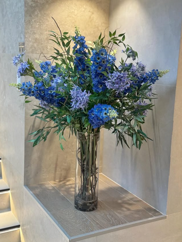 Arreglo Floral de Delphiniums y Agapanthus con Follajes Artificiales en Florero de Vidrio