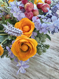 Arreglo Floral con Ranúnculus, Lavandas y Follajes Artificiales en Base Cuadrada de Vidrio y Agua Acrílica