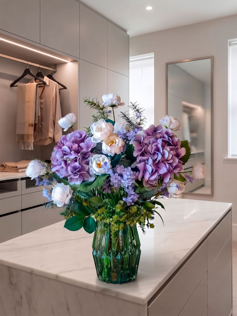 Arreglo Floral con Camelias, Hydrangeas Lilas y Follajes Artificiales en Florero de Vidrio y Agua Acrílica