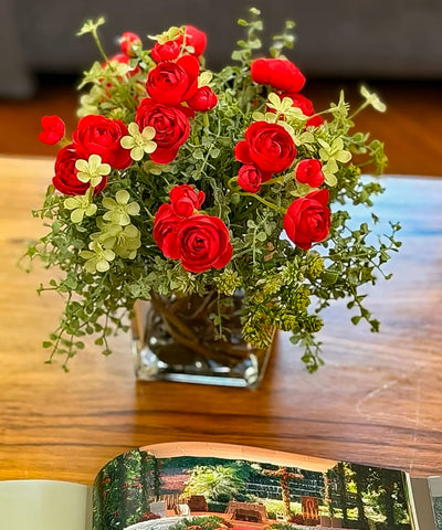 Arreglo Floral con Ranunculus Rojos y Follajes Artificiales en Base Cuadrada de Vidrio y Agua Acrílica