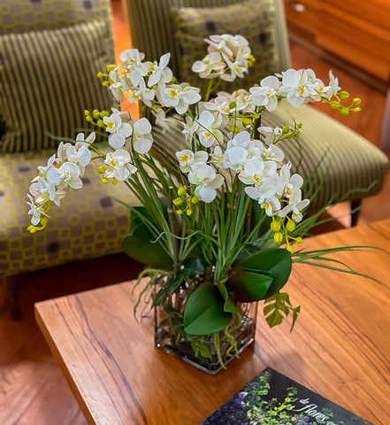 Orquideario con Mini Phalaenopsis y Follajes Artificiales en Florero Cuadrado de Vidrio con Agua Acrílica
