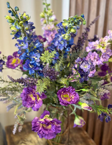 Arreglo Floral de Lisianthus y Delphiniums con Follajes Artificiales en Florero de Vidrio