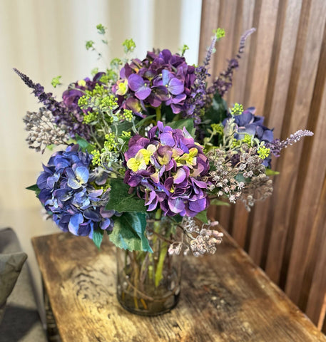 Arreglo Floral con Hidrangeas Lilas y Azules Artificiales en Florero de Vidrio