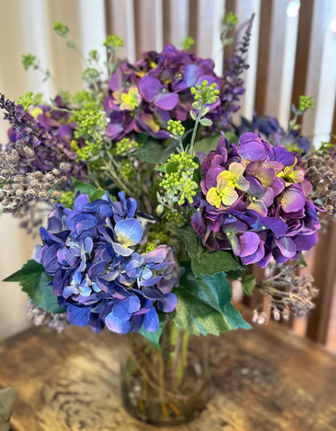 Arreglo Floral con Hidrangeas Lilas y Azules Artificiales en Florero de Vidrio