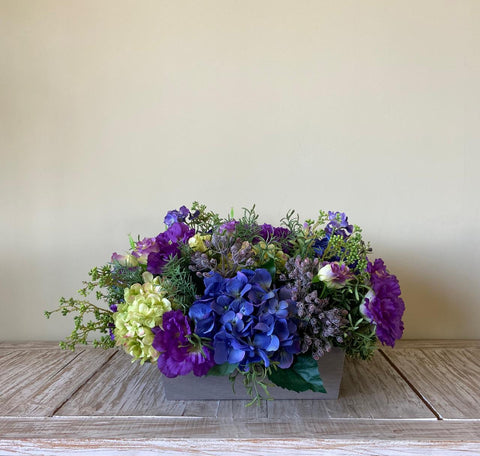 Centro de Mesa de Hidrangeas y Lisianthus con Follajes Artificiales en Base Cuadrada