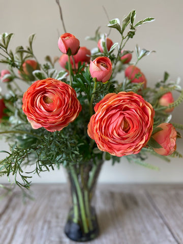 Arreglo Floral con Ranunculus Naranjas y Follajes Artificiales en Florero de Vidrio