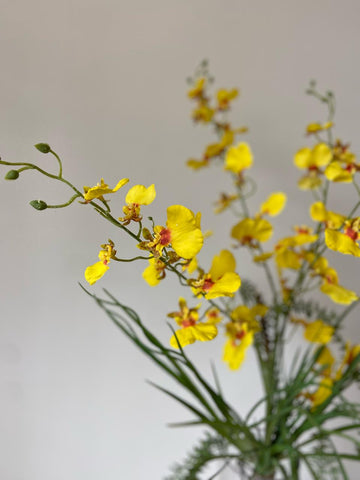 Orquideario con Oncidium Amarilla con Follajes Artificiales en Florero de Vidrio
