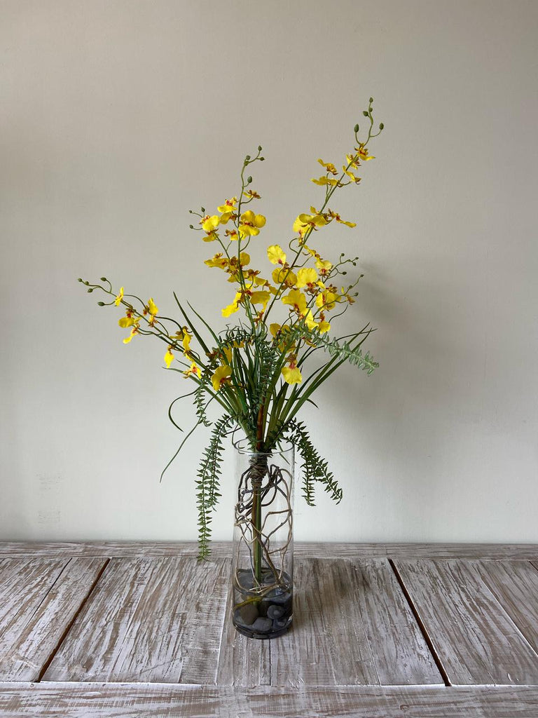 Orquideario con Oncidium Amarilla con Follajes Artificiales en Florero de Vidrio