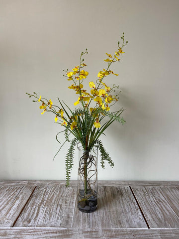 Orquideario con Oncidium Amarilla con Follajes Artificiales en Florero de Vidrio