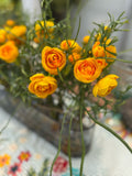 Centro de Mesa con Ranunculus y Follajes Artificiales en Base Ovalada de Vidrio