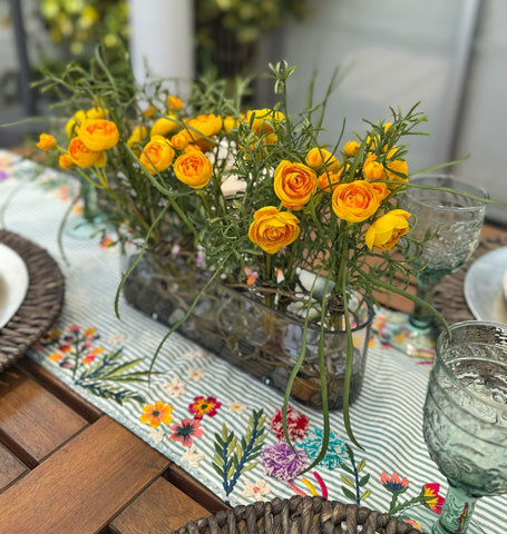 Centro de Mesa con Ranunculus y Follajes Artificiales en Base Ovalada de Vidrio