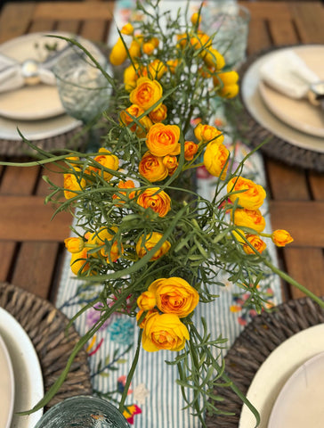 Centro de Mesa con Ranunculus y Follajes Artificiales en Base Ovalada de Vidrio
