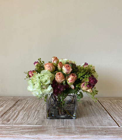 Arreglo Floral con Rosas e Hidrangeas con Follajes Artificiales en Base Cuadrada de Vidrio