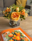 Arreglo Floral con Rosas Amarillas y Follajes Artificiales en Base Cuadrada de Vidrio
