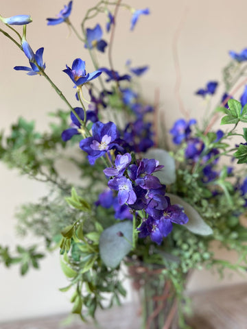 Arreglo Floral con Delphinium Azul y Follajes Artificiales en Florero de Vidrio