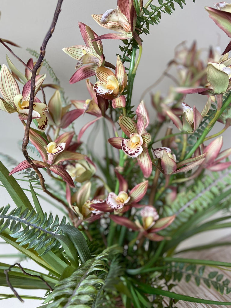 Orquideario con Cymbidium y Follajes Artificiales en Florero de Vidrio