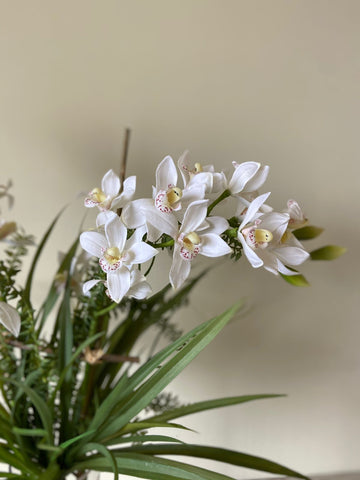 Orquideario con Dendrobium Blanca y Follajes Artificiales en Florero de Vidrio