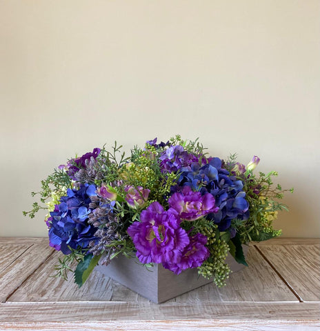 Centro de Mesa de Hidrangeas y Lisianthus con Follajes Artificiales en Base Cuadrada