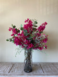 Arreglo Floral con Bougainvilleas y Follajes Artificiales en Florero de Vidrio