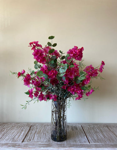Arreglo Floral con Bougainvilleas y Follajes Artificiales en Florero de Vidrio