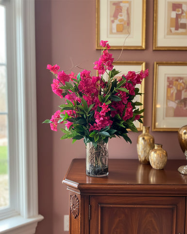 Arreglo Floral con Bougainvilleas y Follajes Artificiales en Florero de Vidrio