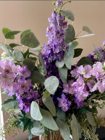 Arreglo Floral con Delphinium Lila y Follajes Artificiales en Florero de Vidrio