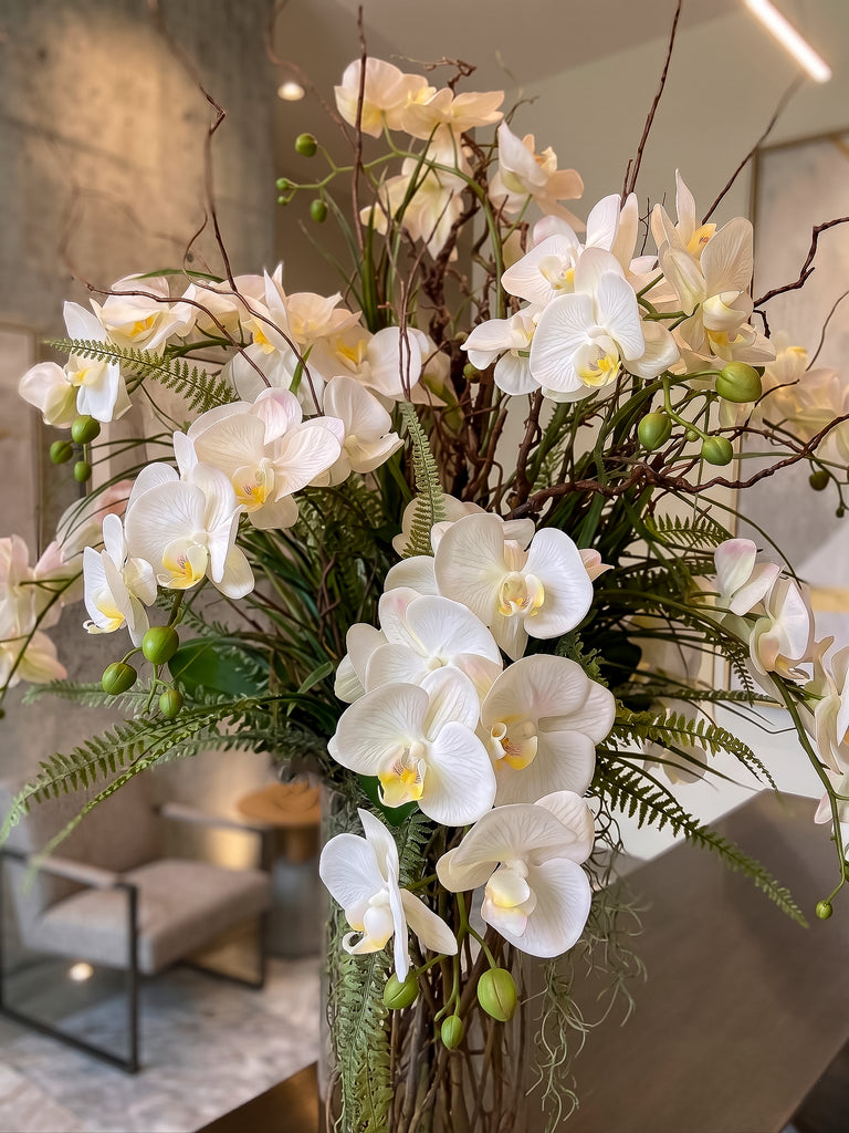 Orquideario con Phalaenopsis Blancas y Follajes Artificiales en Florero de Vidrio con Agua Acrílica