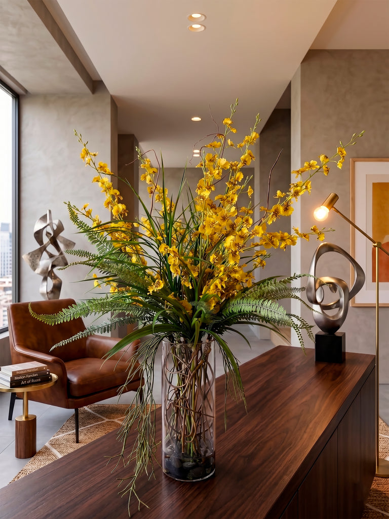 Orquideario con Oncidium Amarilla y Follajes Artificiales en Florero de Vidrio