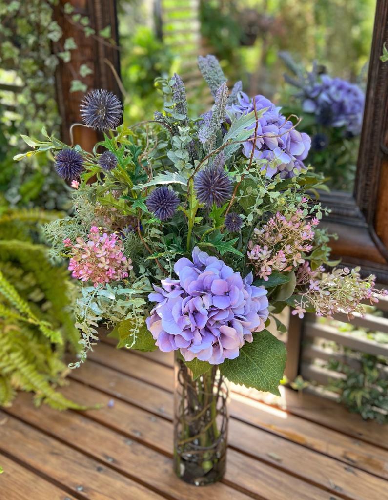 Arreglo Floral de Hydrangeas Lavandas y Follajes Artificiales en Cilindro de Vidrio con Agua Acrílica